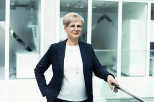 Doc. dr. Jurgita Stravinskienė, pasitikinti savimi, stovi &scaron;viesiame KTU "Slėnio" koridoriuje, vilkinti tamsiu &scaron;varku.